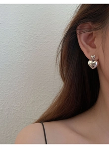 Gros plan de boucles d'oreilles double cœur en argent portées par un mannequin femme