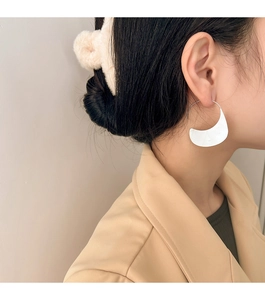 Close-up of model wearing silver large crescent hoop earrings with matte geometric texture