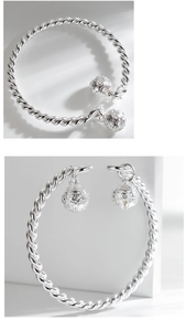 Macro detail of twisted silver bangle featuring double hollow patterned bell charms