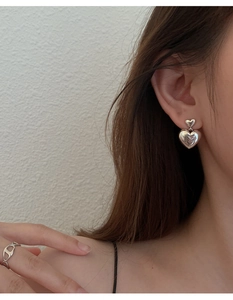 Gros plan détaillé des boucles d'oreilles double cœur en argent s925 portées par modèle