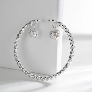 Detail of twisted silver bangle with traditional floral engraved double bell pendants