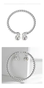 Detailed view of silver twisted cable bracelet with two engraved hollow bell charms