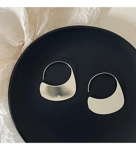Detailed macro shot of irregular silver S925 moon hoop earrings on a black display base