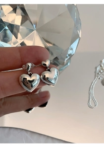 Gros plan de boucles d'oreilles cœur en argent s925 avec double design cœur et éclat miroir