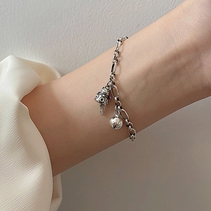 Retro silver charm bracelet with dual bells and peace engraving on a woman's wrist
