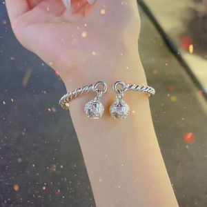 Detail of twisted silver-tone cuff bracelet with hollow bell charms on female wrist