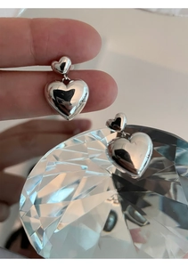 Vue macro des boucles d'oreilles cœur en argent S925 avec finition polie miroir