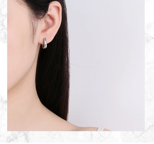 Gros plan d'un modèle portant des boucles d'oreilles géométriques en argent à double couche