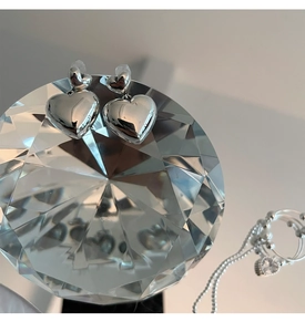 Vue macro de boucles d'oreilles cœur en argent massif S925 sur un prisme en cristal