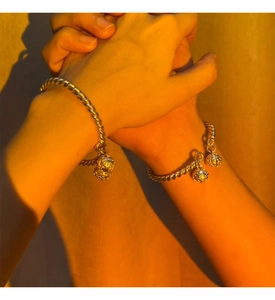 Close-up of twisted silver-style open bangles with hollow bell pendants for women