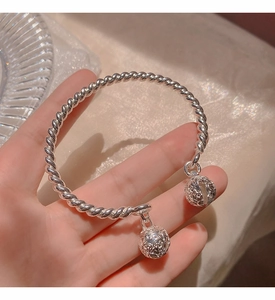 Detailed macro view of silver twisted rope bangle featuring two intricate hollow bell charms