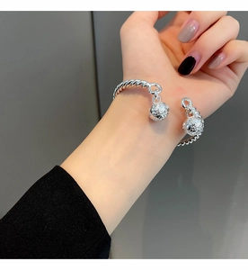 Detail of silver twisted rope cuff bracelet with dual vintage engraved bells on model