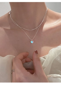 Detail of s925 silver layered necklace featuring heart pendant with aurora stone on a model