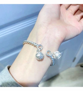 Close-up of twisted silver cuff bracelet with delicate hollow flower bell charms