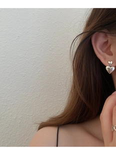 Gros plan de boucles d'oreilles cœur en argent portées par un mannequin avec éclairage naturel