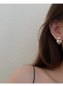 Gros plan d'un mannequin portant des boucles d'oreilles cœur en argent S925 poli miroir