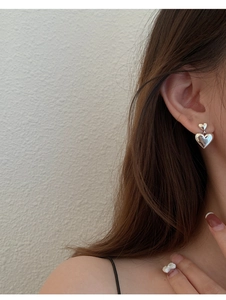 Gros plan d'un modèle portant des boucles d'oreilles cœur en argent s925 poli miroir