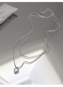 Macro shot of 925 silver double layer heart necklace with moonstone pendant and reflection