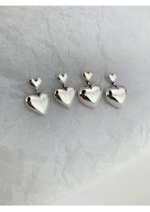 Gros plan de boucles d'oreilles cœur en argent S925 avec finition miroir sur papier texturé