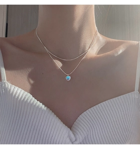 Detail of double-layer silver necklace with a blue heart-shaped opal pendant on a model