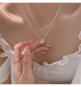 Close-up of double-layered silver necklace with heart-shaped iridescent stone pendant