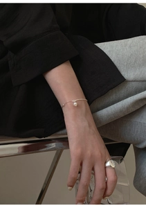 Minimalist silver pearl bracelet and wide band ring set worn by a female model
