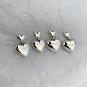 Paire de boucles d'oreilles cœur en argent massif S925 sur un fond gris texturé
