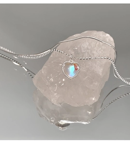 Detail of 925 sterling silver heart necklace with iridescent stone on a crystal base