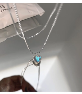 Macro shot of silver heart pendant with iridescent moonstone on a delicate bead chain