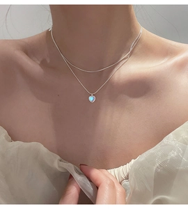 Close-up of double-layer silver necklace featuring a heart-shaped blue moonstone pendant