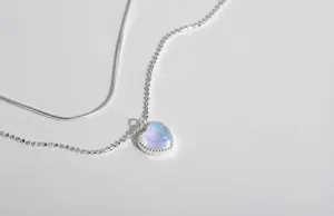 Macro shot of S925 silver double-layered heart pendant with moonstone and bead edging