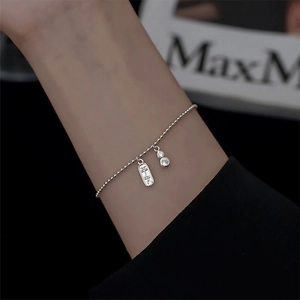 Détail du bracelet à billes argentées avec breloque Pingan et pendentif gourde serti