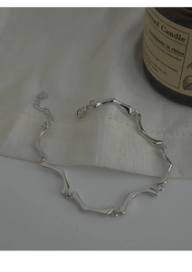 Gros plan d'un bracelet argenté aux maillons ondulés avec pendentif cœur et fermoir