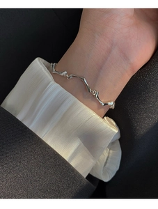 Gros plan d'un bracelet en métal liquide argenté porté au poignet d'un mannequin