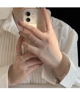Dettaglio di anelli minimalisti in argento con texture a foglia e bracciale a catena doppia