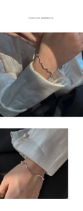 Gros plan du bracelet à maillons ondulés argentés porté au poignet avec de la soie