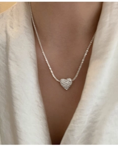 Macro detail of a silver lava heart pendant necklace with shimmering zircon stones
