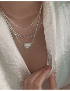 Detail of triple-layer necklace with lava texture heart pendant and pearls on model