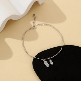 Détail du bracelet en perles argentées avec plaque Pingan et breloque gourde chinoise