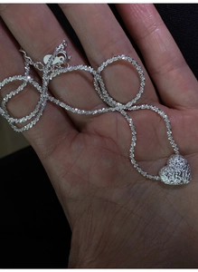 Macro shot of silver lava textured heart pendant with sparkling starry chain detail