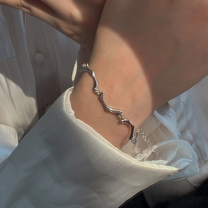 Bracelet à maillons argentés minimaliste style osselet porté au poignet avec chemise