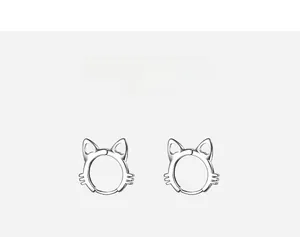 Macro detail of cat-shaped silver earrings featuring hollow heart cutout design