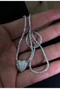 Macro detail of silver heart pendant with lava texture and shimmering star chain