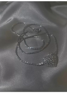 Macro shot of a silver heart pendant with shimmering crystals on a silk fabric background
