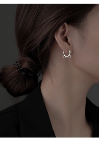 Close-up of a silver cat ear hoop earring worn by a model in a minimalist style