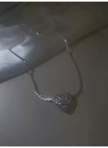 Macro view of silver heart pendant featuring a unique molten lava textured surface