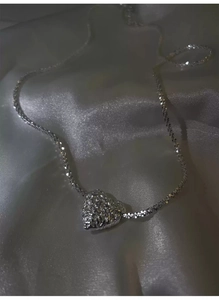 Macro detail of silver heart pendant with lava texture on shimmering star chain