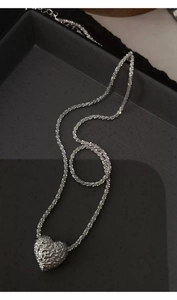 Macro detail of the silver lava textured heart pendant on a sparkling starry chain necklace