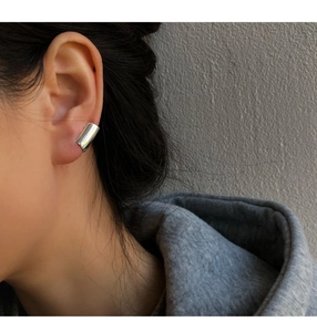 Close-up of minimalist silver geometric ear cuff showing high-polish mirror finish on ear
