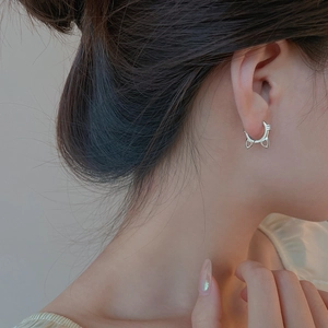 Close-up of minimalist cat-shaped silver hoop earring worn on a model's ear